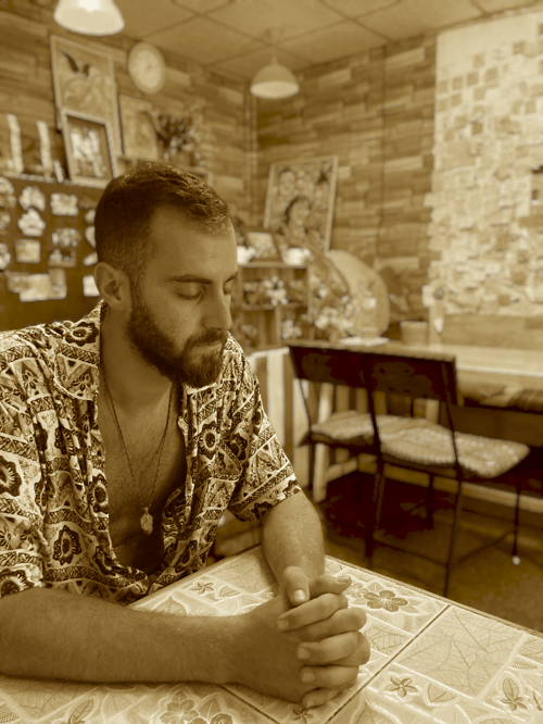 This image captures Michail Kyriakakis, the author of "Life Has Two Doors: A Mystical Journey of Self-Discovery and Timeless Wisdom," in a serene, reflective pose. The setting conveys an intimate atmosphere of artistic expression and deep thought, mirroring the themes of transformation, spirituality, and personal growth that define his work. Michail’s contemplative nature is seen through this candid moment, embodying the journey his readers embark upon through his words.