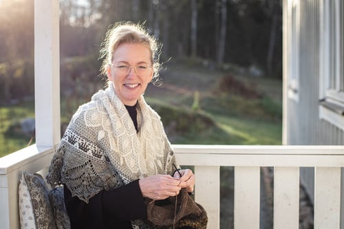 Portrait of Anne-Lise Maigaard knitting on porch in the woods