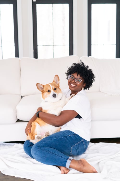 Therapist Elizabeth Bullard in a white top and jeans holding her brown and white corgi Preston