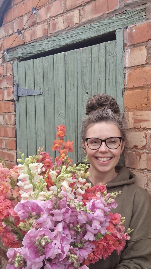 Kate from Homegrown Blooms holding a bunch of snapdragons