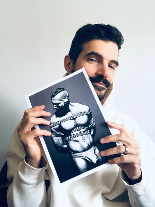 The portrait of the artist Dany Dee holding one of the prints of his drawings in hands