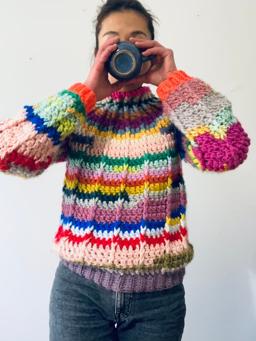 store owner wearing a handmade pullover drinking a coffee