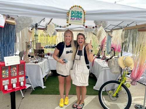 Two artists at an art show selling handmade goods and hand painted unique bike bells.