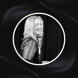 Blonde woman standing behind a microphone holding a ukulele