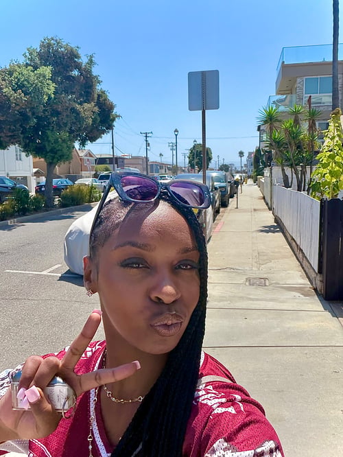 Deja, creator of Slim Samone, outdoors in California wearing a red outfit