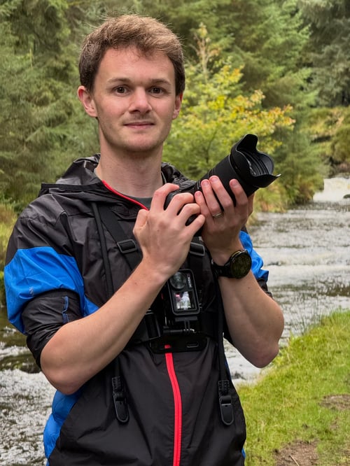 Davidson Photography independent photographer holding a camera outdoors in a woodland setting.