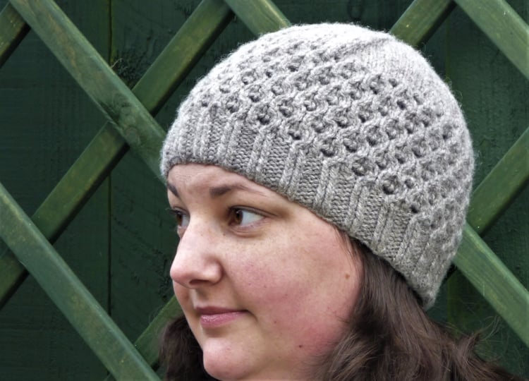 Grey wool knitted hat with all over lace pattern. Handmade in the UK by Su Sayer.