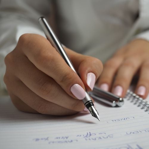 Woman writing with a fountain pen on a spiral notebook
