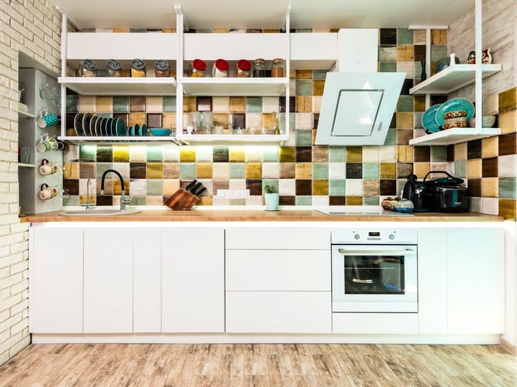 How to choose an accent wall. Square tiles in cohesive colors as an accent behind open shelving in this kitchen. Coordinating paint color palettes by Lavenia Shash.
