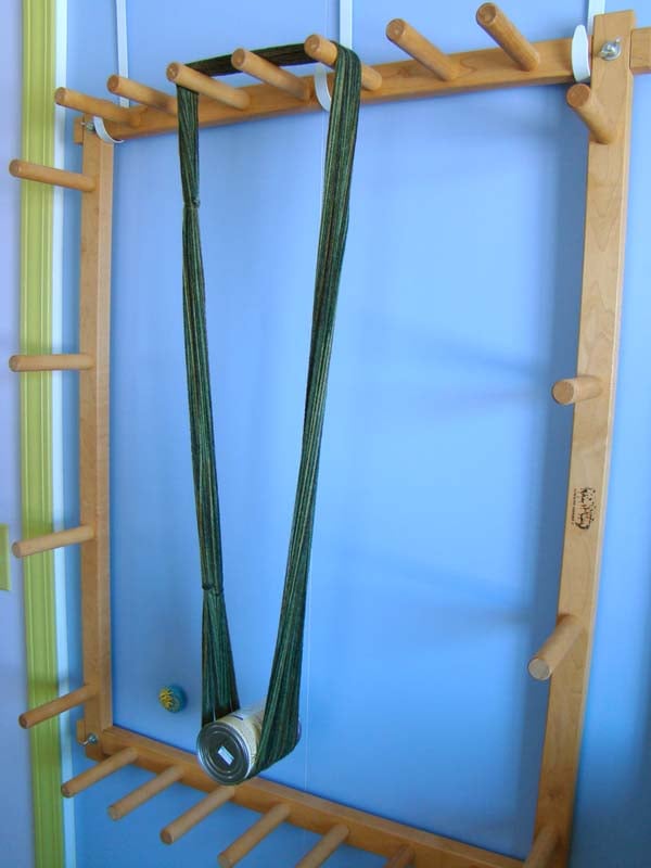 yarn hanging from a wood rack with a can of beans for weight