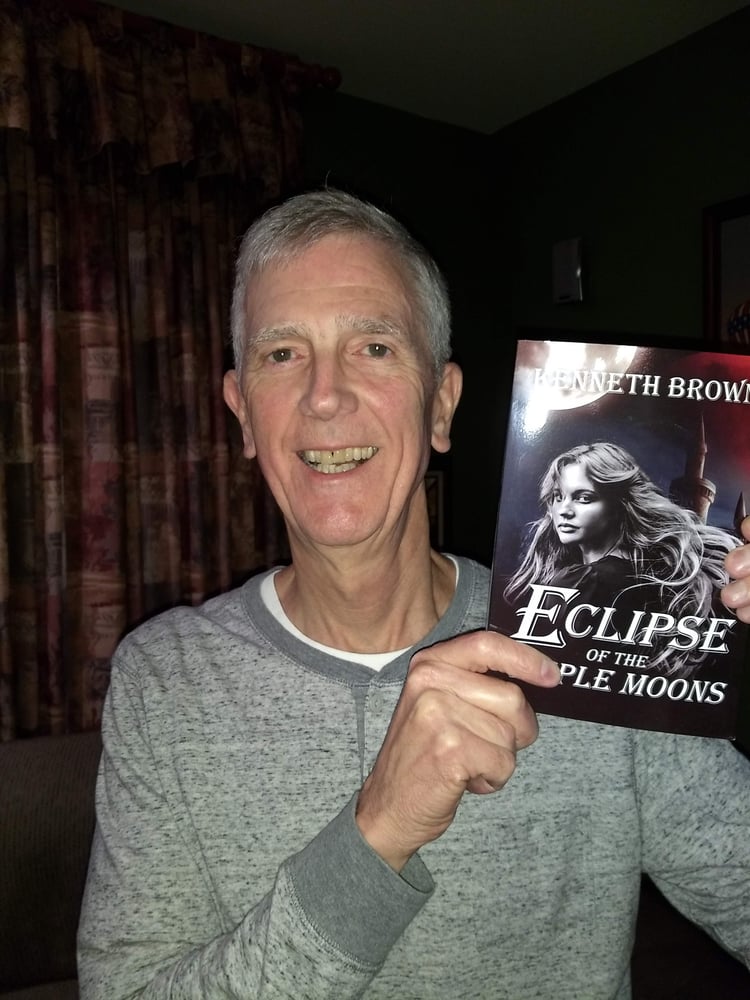Eclipse of the Triple Moons Paperback book being held by author Kenneth Brown