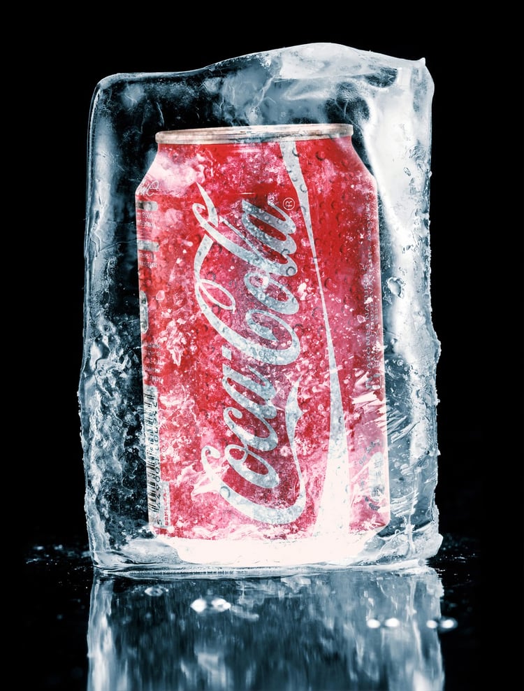 Coca-Cola can inside an ice block behind a black background