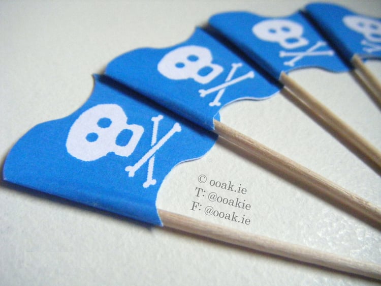 Sheet of 25 blue and white printable Jolly Roger flags for a boys pirate birthday or nautical cupcake decor.