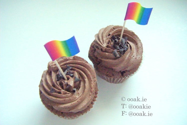 Two Rainbow gradient flags used as cupcake toppers on chocolate cupcakes