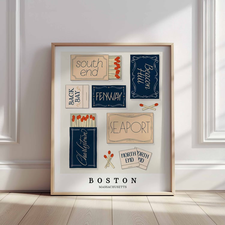 A framed picture of Boston, Massachusetts neighborhoods drawn in various lettering styles on matchboxes. Artwork has a navy blue, beige and tan color scheme