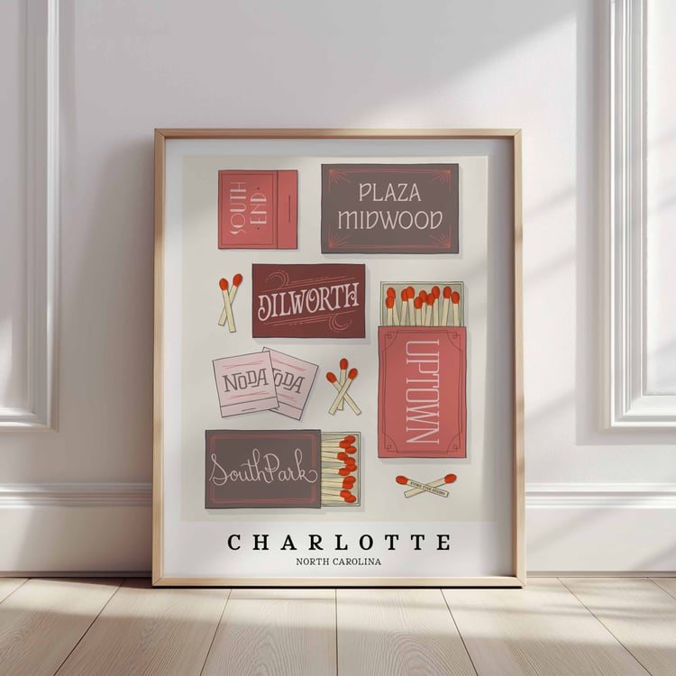 A framed picture of Charlotte, North Carolina neighborhoods drawn in various lettering styles on matchboxes. Artwork has a pink, burgundy and gray color scheme