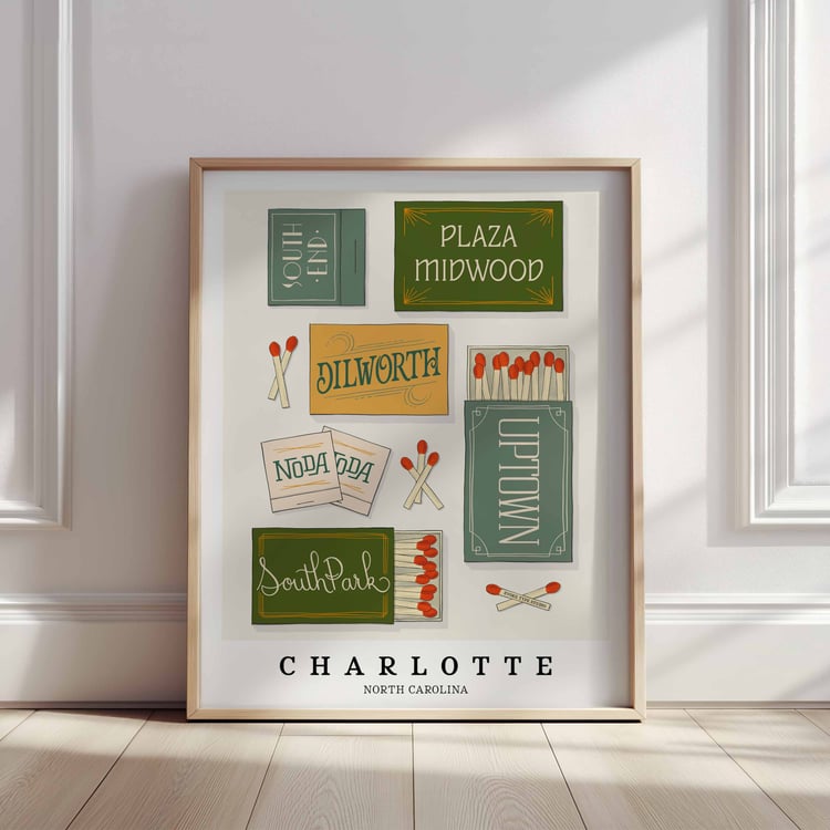 A framed picture of Charlotte, North Carolina neighborhoods drawn in various lettering styles on matchboxes. Artwork has a blue, green and yellow color scheme