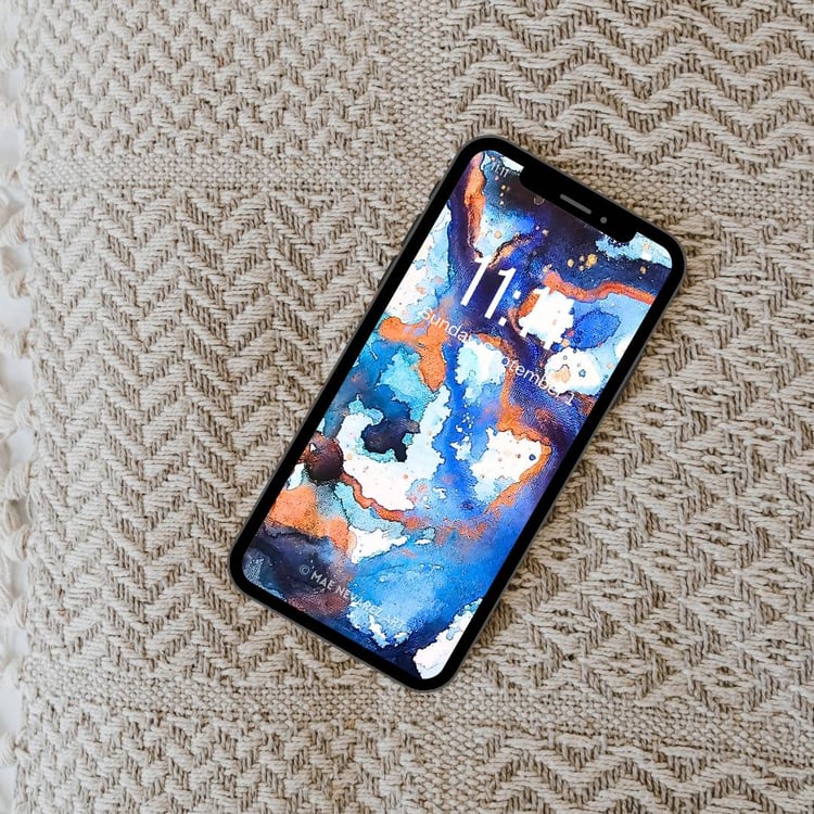 Abstract phone wallpaper featuring deep cobalt, blue, and bronze hues with a cosmic-inspired design and shimmering metallic accents.