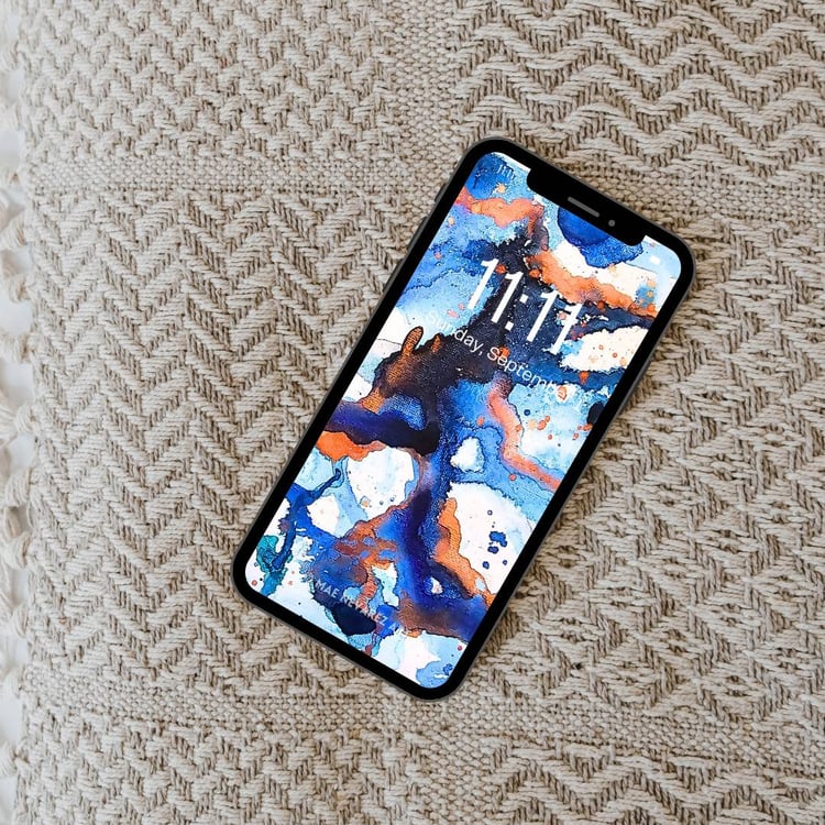 Abstract phone wallpaper featuring deep cobalt, blue, and bronze hues with a cosmic-inspired design and shimmering metallic accents.