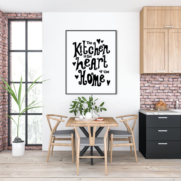 A large print hung over a kitchen table and chairs which reads, "The Kitchen Is The Heart Of The Home".