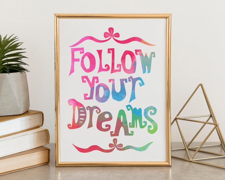 Follow Your Dreams print on desk with books and a geometric shape.