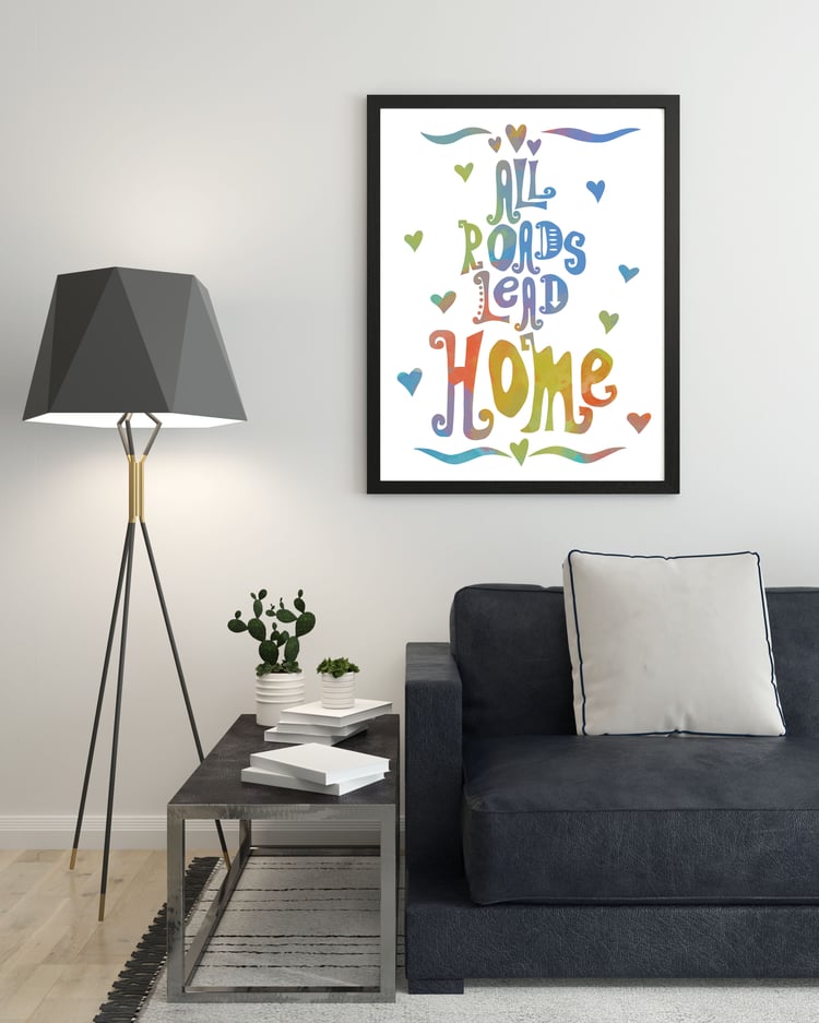 All Roads Lead Home print hung over a dark grey sofa next to a floor lamp with a dark grey shade.