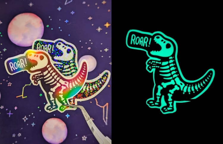 The sticker features a playful, skeleton version of a T-Rex dinosaur. The dinosaur has small, comically short arms and is positioned as if roaring, with the word ROAR! in a speech bubble above its head. The sticker glows in the dark, providing a soft, glo