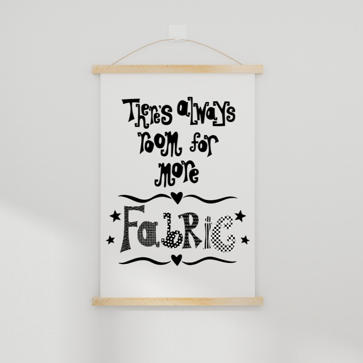 A downloadable print with a hand lettered design which says ‘there’s always room for more fabric’ in black.  Shown hanging on a wall in a simple wooden poster hanger.