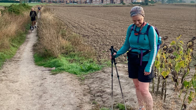 A female hiker carrying hiking poles on the Camino reflecting on her journey