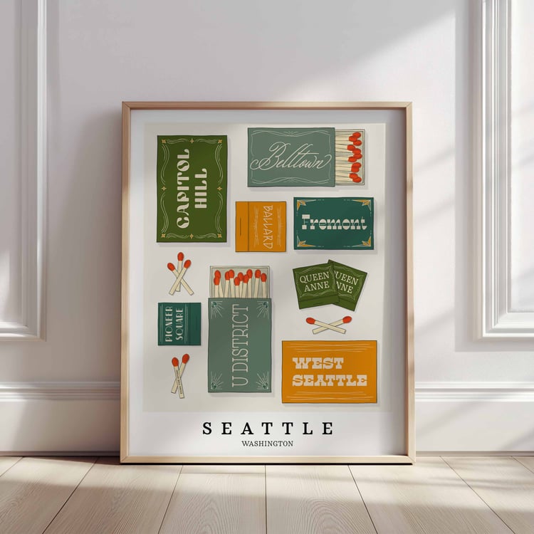 A framed picture of Seattle, Washington neighborhoods drawn in various lettering styles on matchboxes. Artwork has a green, blue and yellow color scheme