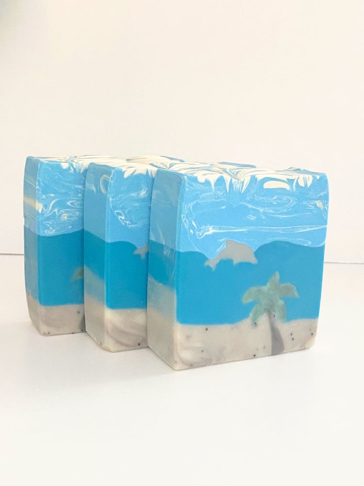 Handmade artisan dolphin beach soap embedded with a design showing a dolphin in the water beyond the beach