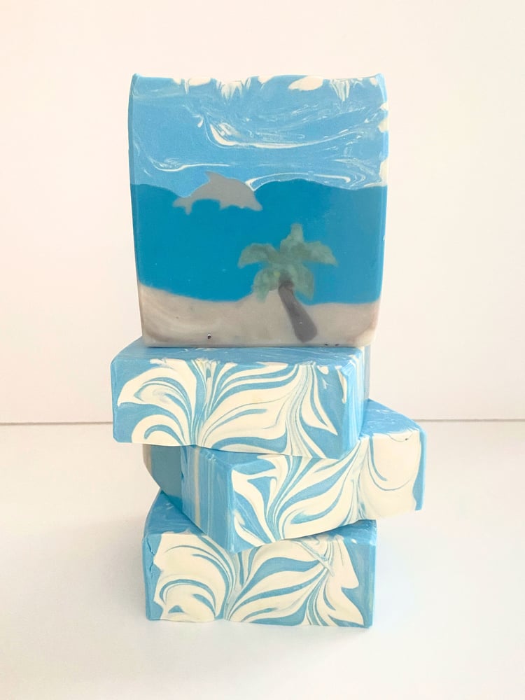 Handmade artisan dolphin beach soap embedded with a design showing a dolphin in the water beyond the beach