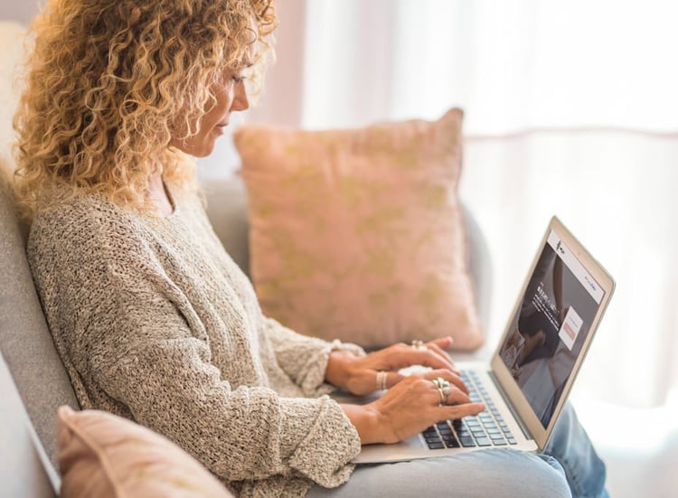 woman sitting in a sofa receiving a weekly email on her laptop