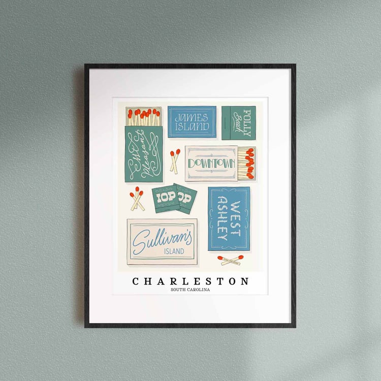 A framed picture of Charleston, South Carolina neighborhoods drawn in various lettering styles on matchboxes. Artwork has a coastal color scheme of blue, green and beige.