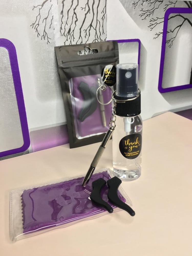 Main Frame Eyeglasses Care Kit with cleaning spray, microfiber cloth, 4-in-1 screwdriver, and silicone ear hooks arranged neatly.