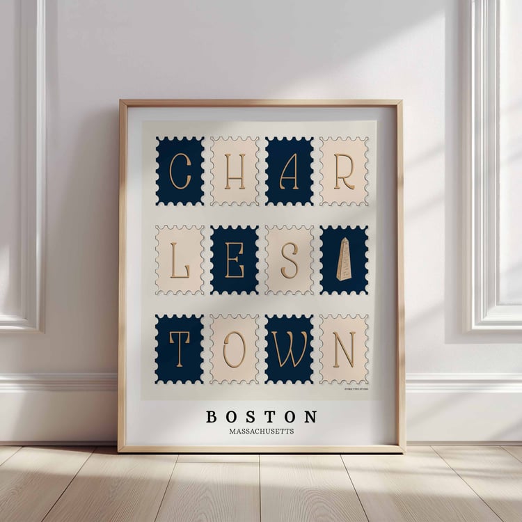 A framed picture of postage stamps featuring the Charlestown neighborhood in Boston, Massachusetts drawn in a unique lettering style. Artwork has a nautical color scheme of navy blue and beige
