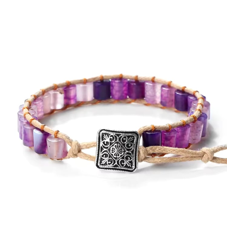 Artisan-crafted wrap bracelet featuring polished purple, lilac, and deep violet gemstone barrel beads, intricately woven onto a light brown natural cord, and secured with a decorative square antique-silver style button clasp.