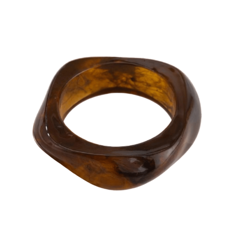 Product shot of a chunky wide cuff bangle bracelet crafted from polished resin, featuring a translucent dark brown and amber tortoiseshell pattern. The statement bracelet has a unique organic, softened square shape.