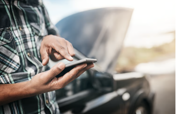 person standing by a car texting for help