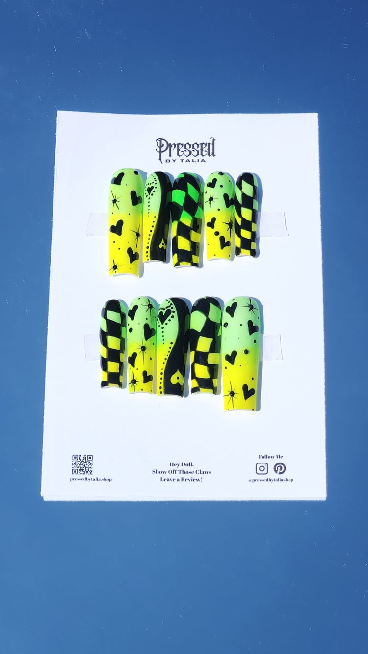 Long square shaped press-on nails with lemon yellow and lime green neon pigment powder ombre, hand painted checkered print designs in black gel polish, yin and yang heart designs in black, and hearts and stars designs in black, add black rhinestones
