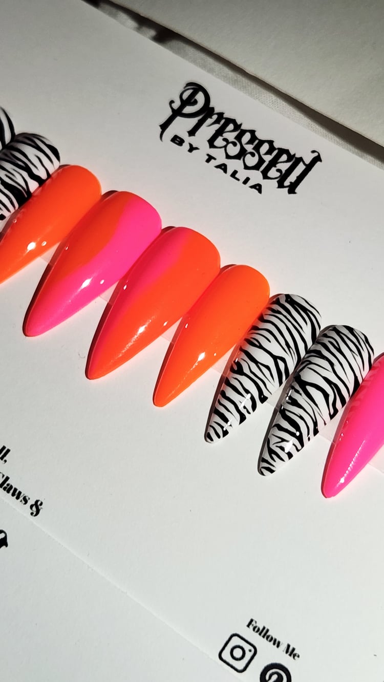 Medium length stiletto shaped press-on nails with hot pink and neon orange ombre and handmade zebra printed designs, press-on nails, close-up picture on Pressed By Talia branded card