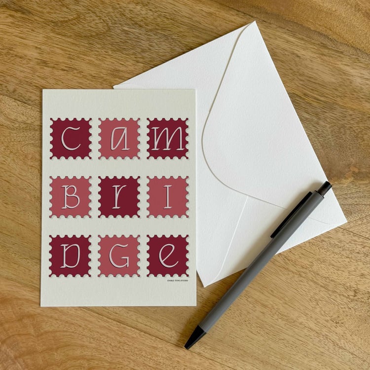 A colorful notecard sitting on a table with a white envelope and pen.