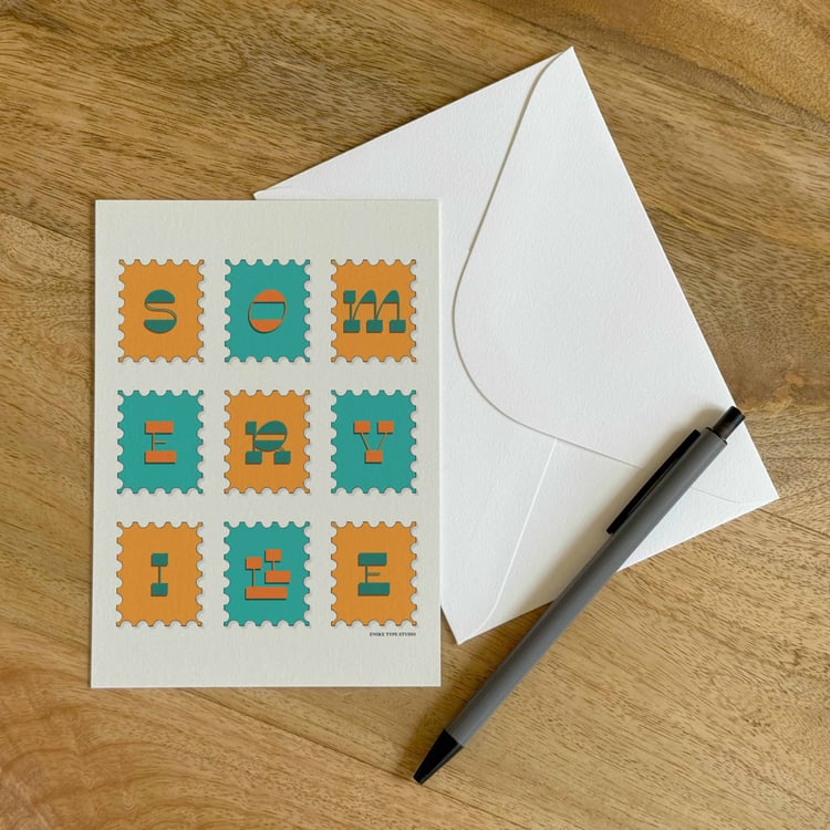 A colorful notecard sitting on a table with a white envelope and pen.