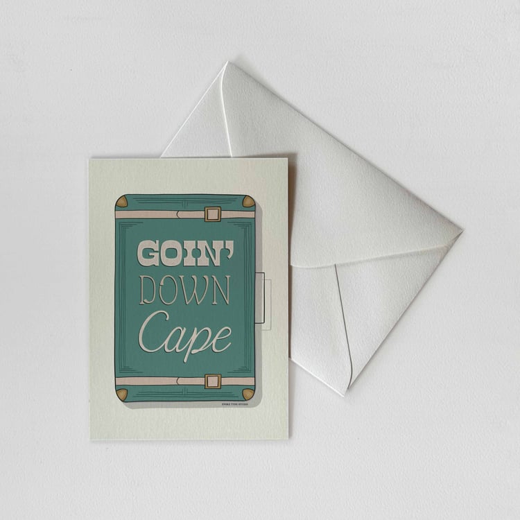A notecard of a vintage style suitcase with the words "Goin Down Cape" drawn on it in unique lettering styles with a white envelope. Artwork has a blue, green and beige color scheme