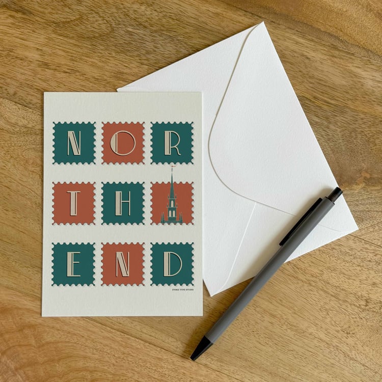 A colorful notecard sitting on a table with a white envelope and pen.