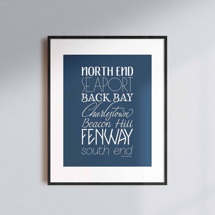 A framed picture of Boston, Massachusetts neighborhoods drawn in various lettering styles. Artwork has a blue and white color scheme