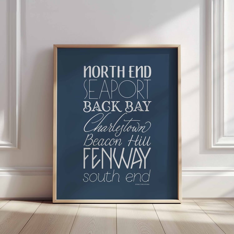 A framed picture of Boston, Massachusetts neighborhoods drawn in various lettering styles. Artwork has a blue and white color scheme