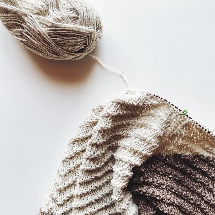 A garment in progress made with textured knit and purl ridges.