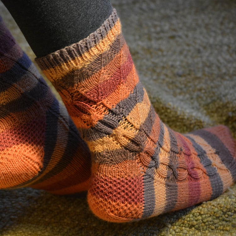 Closeup detail of cuff and top of leg of Beanstalk Socks. The chain cable twists at a gentle slope, hitting just inside the mid-calf point.