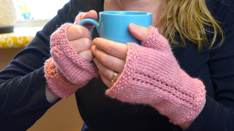 Close-up of the fingerless mitten backs on hands showing the seed stitch border on the top, thumb edge, and the pretty twin rows of eyelets creating the lace "vine" up the back.